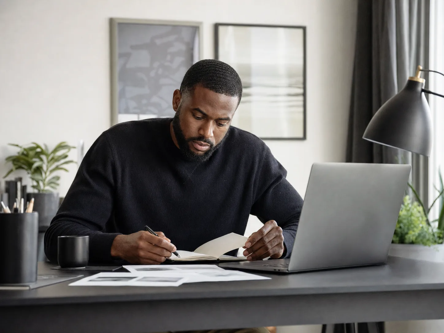 A man reviewing notes beside a laptop at a home desk